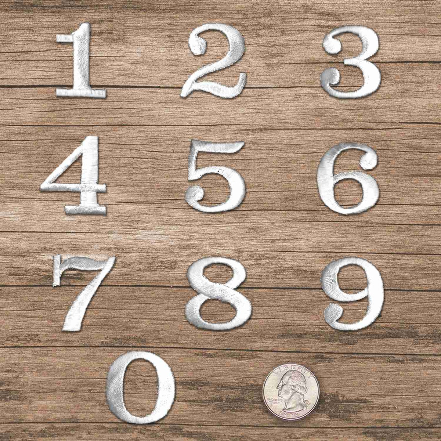 A set of White 0-9 Iron on Patch 1-1/4"H - Sold Separately on a wooden surface.