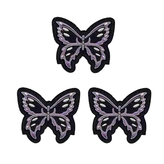 Three Black and Lavender Tribal Butterfly Iron On Patches by Laughing Lizards are arranged in a triangle on a white background, each intricately designed. This 3-pack features the brand’s detailed butterfly design.