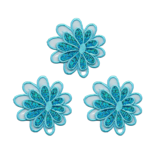 The Laughing Lizards Sparkle Daisy in Blue (3-Pack) Iron On Flower Applique features three blue and teal floral appliques with layered petals, including a light blue daisy patch, arranged on a white background.