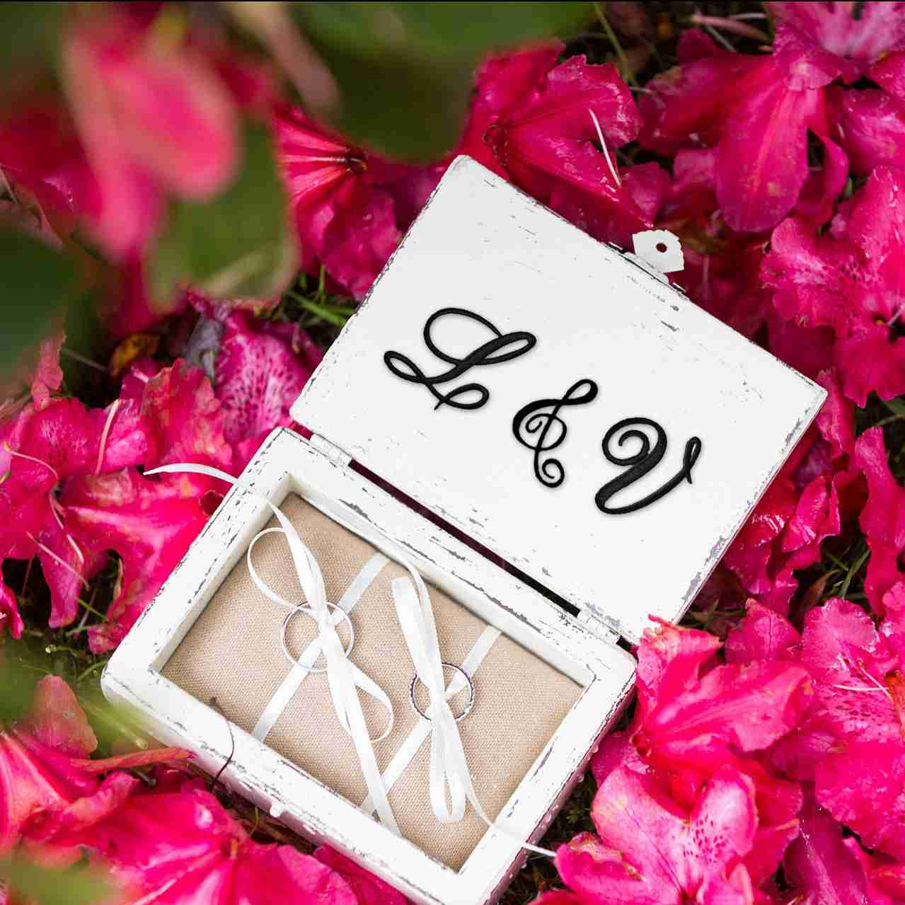 A wooden box with the Iron On Script Letter Patches, Monogram Appliques on it surrounded by pink flowers.