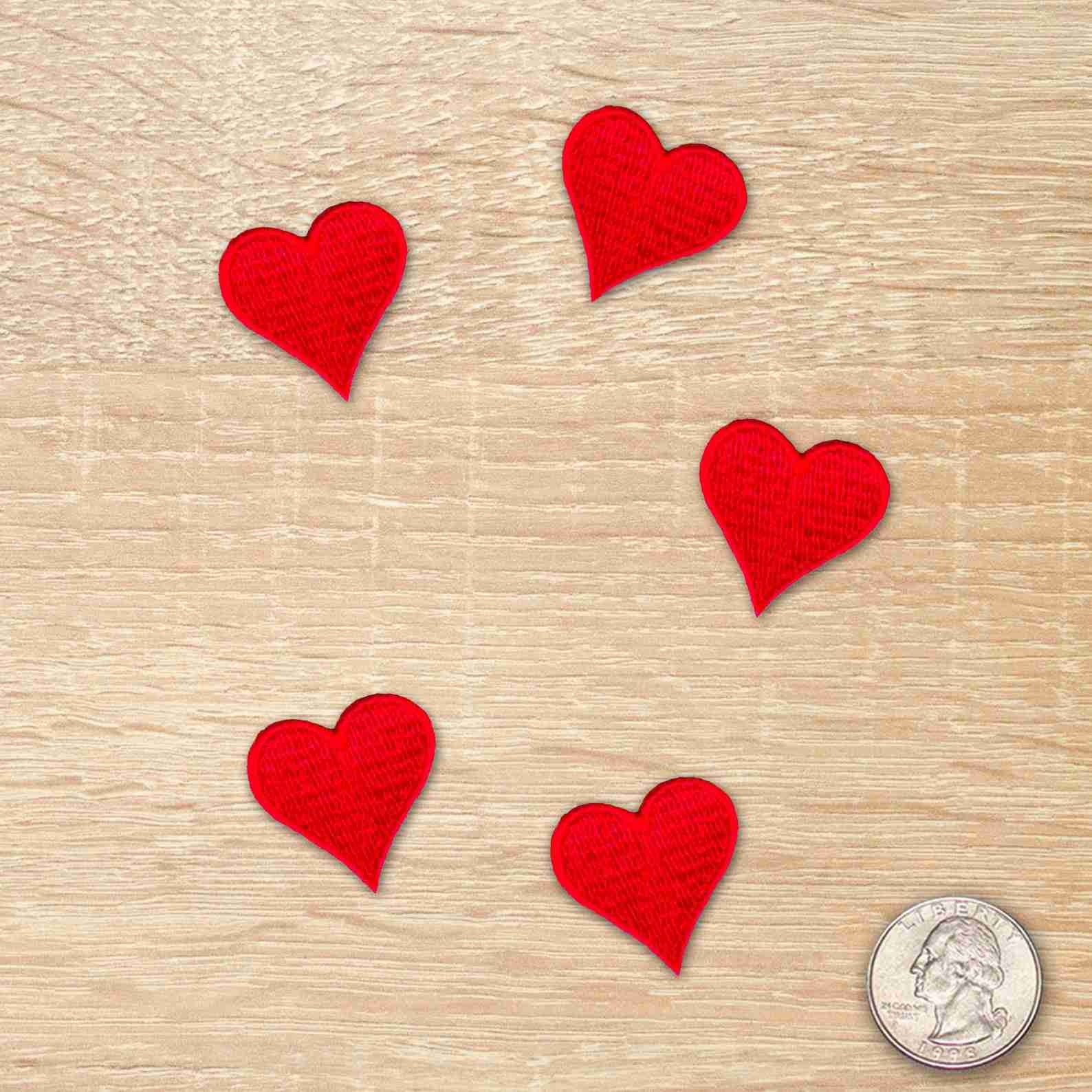 Five Heart Embroidered Iron on Patches (5-Pack) arranged in a circle on a wooden table.