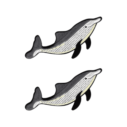 Laughing Lizards Single Dolphin Patches (2-Pack) feature embroidered fish designs in black, gray, white, and a yellow accent. These playful iron-on sea animal patches add charm to any fabric project.