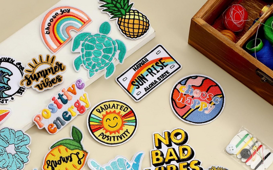 A collection of colorful embroidered patches with positive and summer-themed designs displayed on a flat surface.