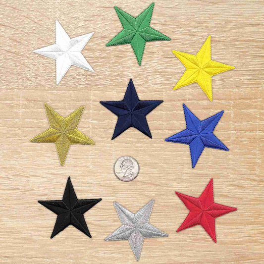 Six 2.5 Inch Star Iron On Patch (5 Pack) appliques on a wooden table.