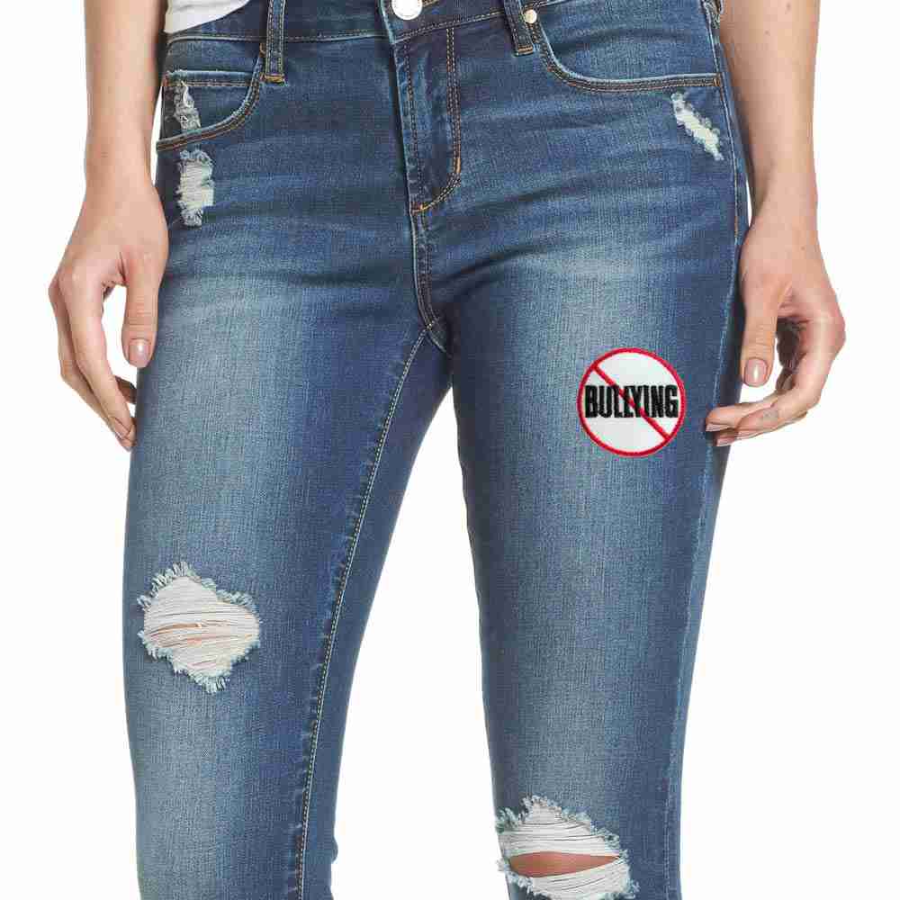 A woman wearing ripped jeans with an Anti-Bullying Sign Iron On Patch on them.