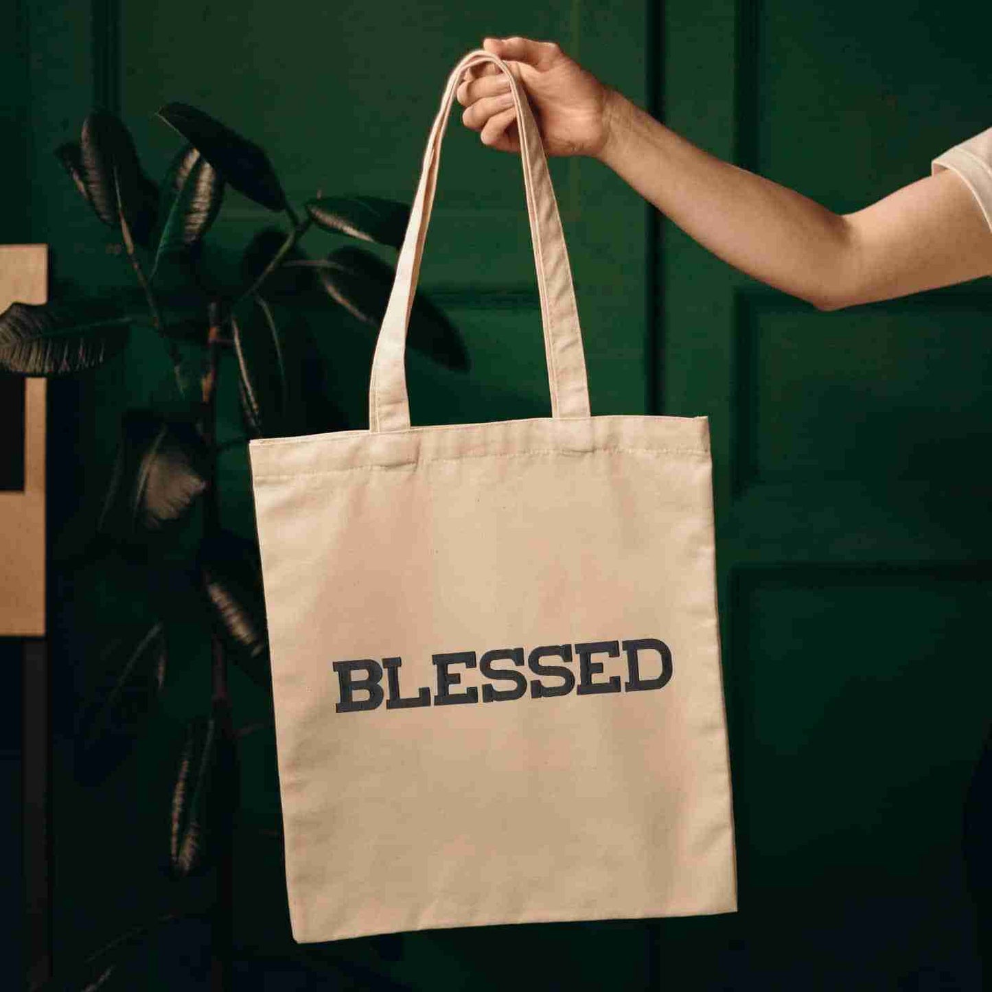 A person holding a tote bag that has Iron On Letter Patches, 2" Block Letters & Numbers on it and says blessed.