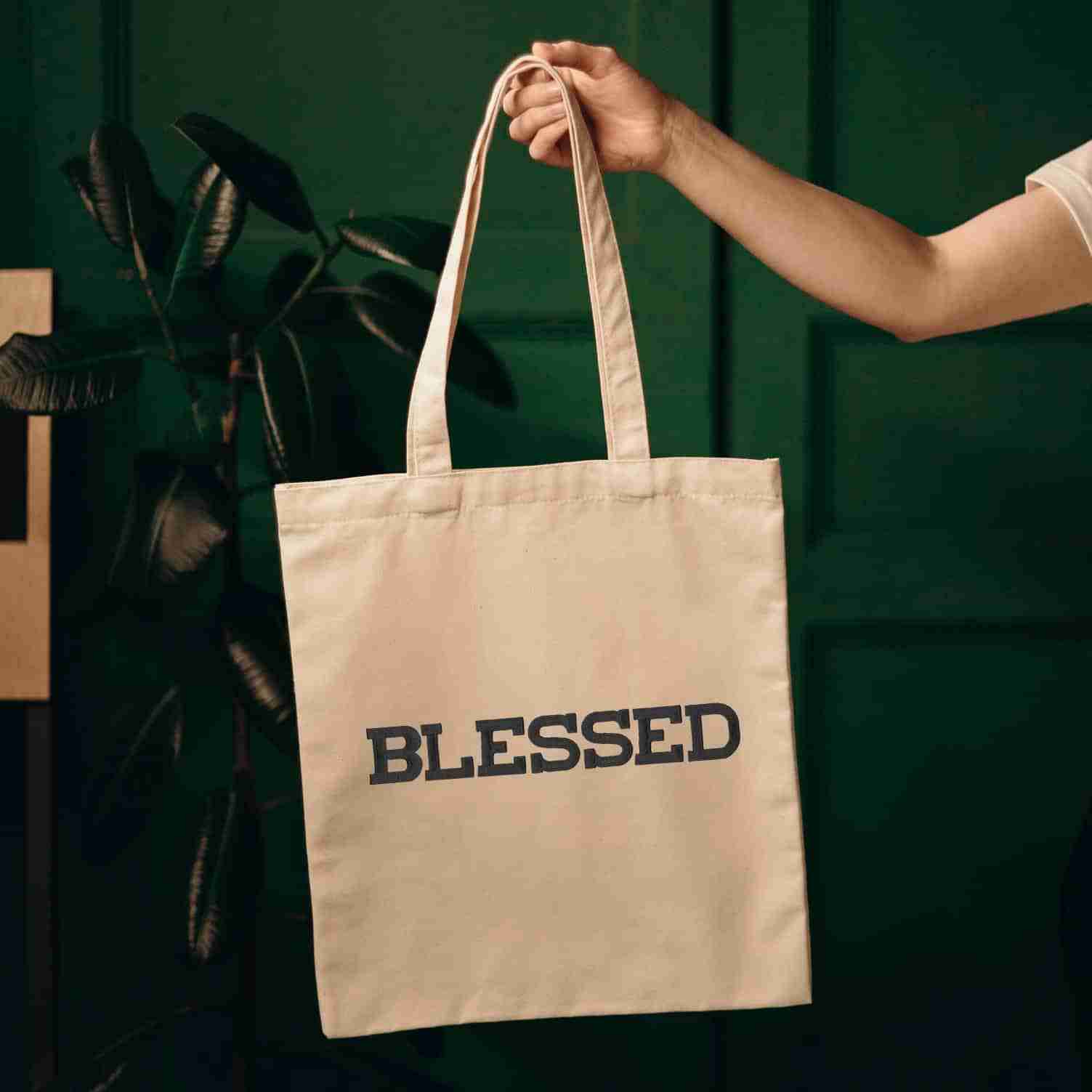 A person holding a tote bag that has Iron On Letter Patches, 2" Block Letters & Numbers on it and says blessed.