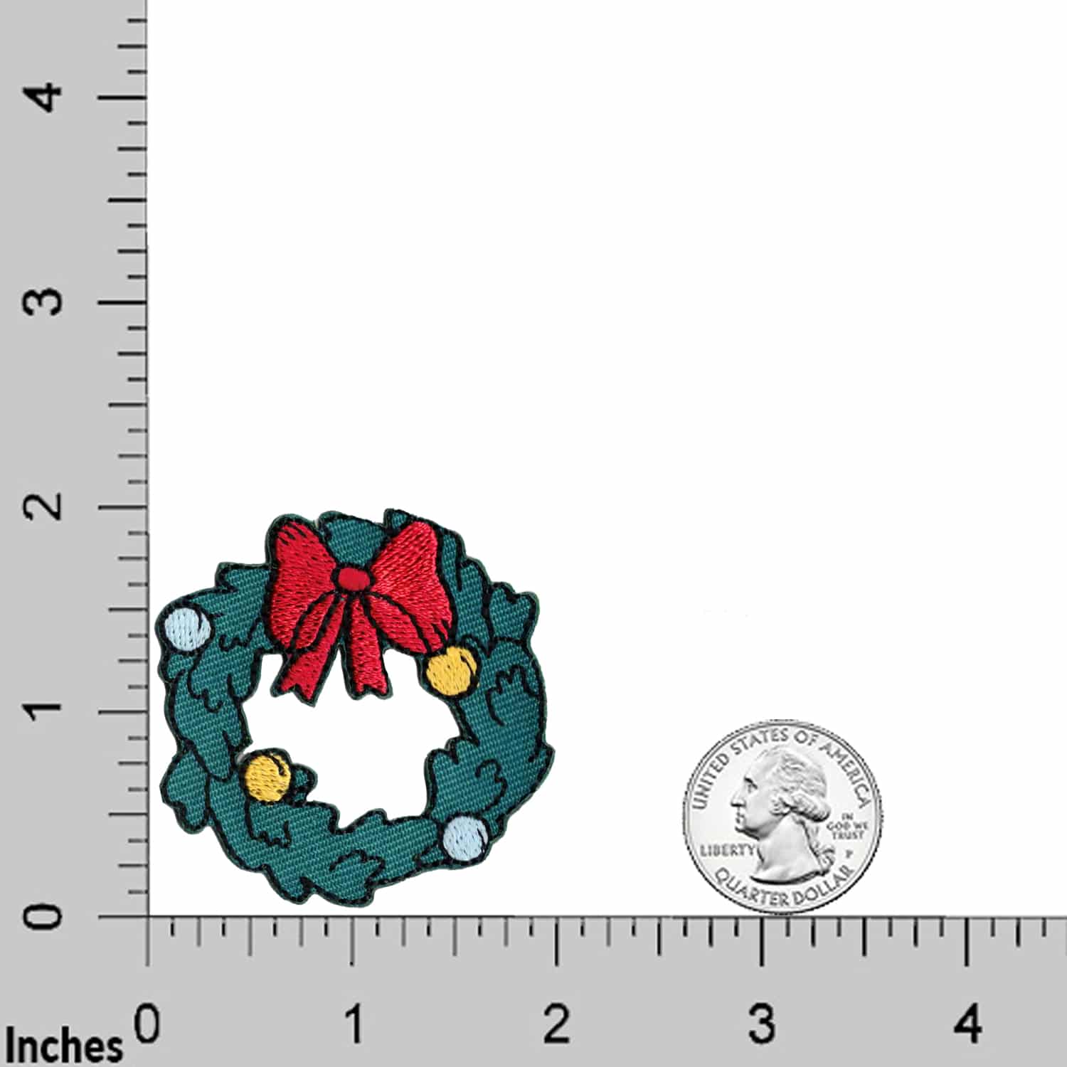 The Laughing Lizards Christmas Wreath (3 Pack) Embroidered Iron on Patch Applique is shown beside a US quarter for scale, on a surface with inch markings.