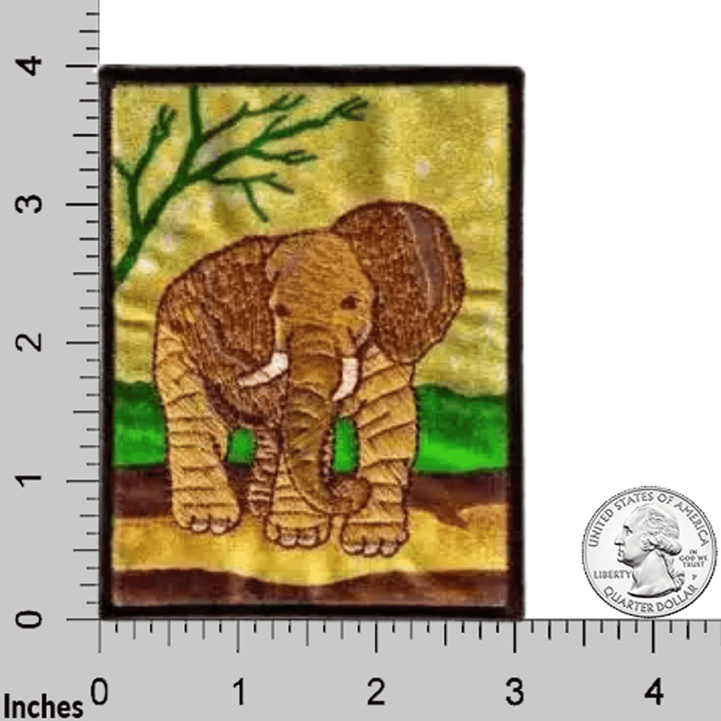 The Laughing Lizards Elephant in Natural Environment Jungle Iron On Patch is a rectangular patch featuring an embroidered elephant standing on grass, shown next to a ruler and U.S. quarter for size reference.