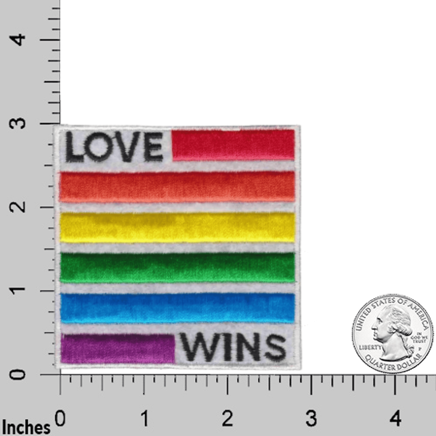 The Laughing Lizards Love Wins Equality (2-Pack) Iron On Patch features rainbow stripes and “LOVE WINS”; shown on a measurement grid with a U.S. quarter for scale.