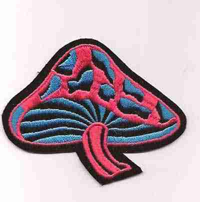 A Black Light looking Pink and Blue Velvet Mushroom Iron On Patch on a white surface.