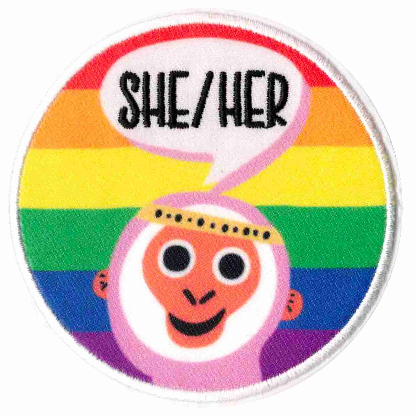 A round patch with the words She/Her on it.