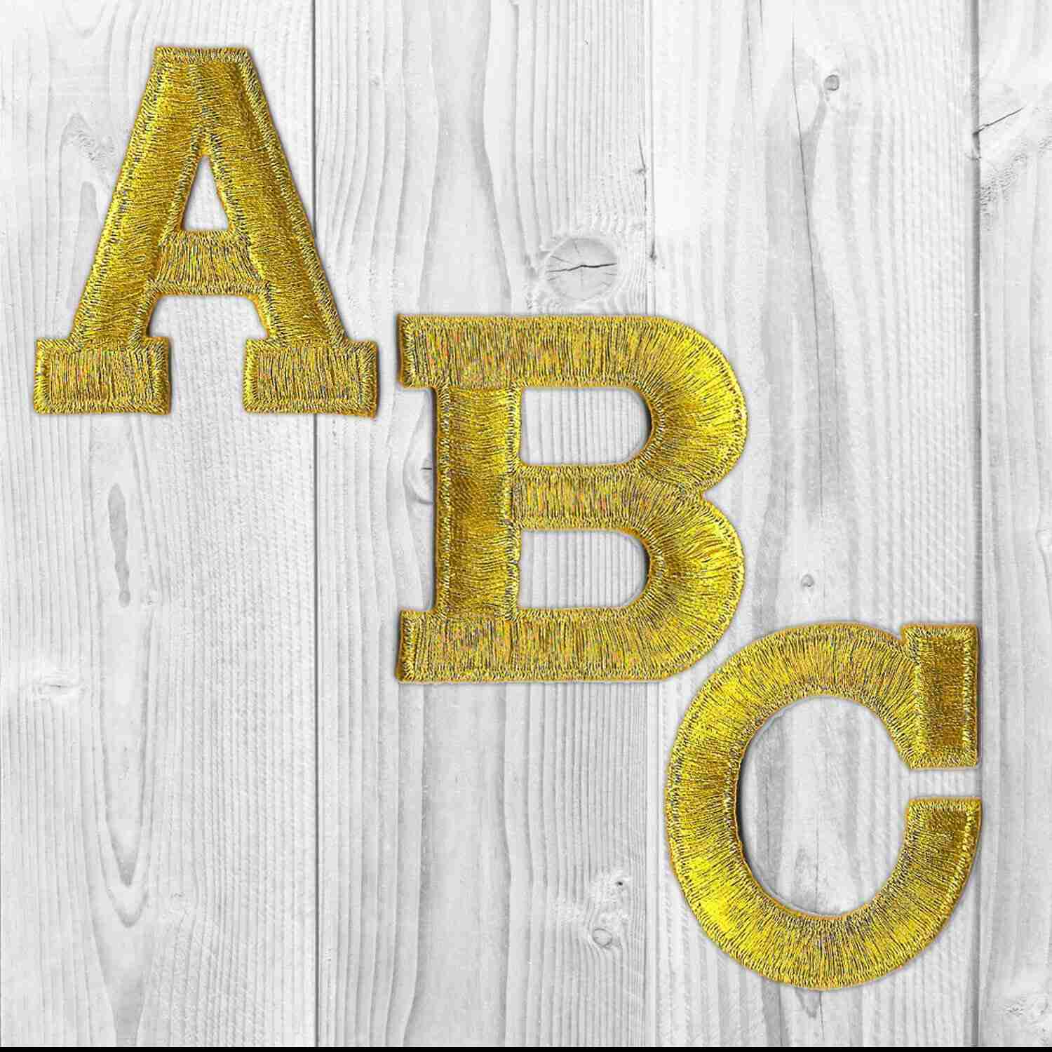 A set of Iron On Letter Patches, 2" Block Letters & Numbers on a wooden background.