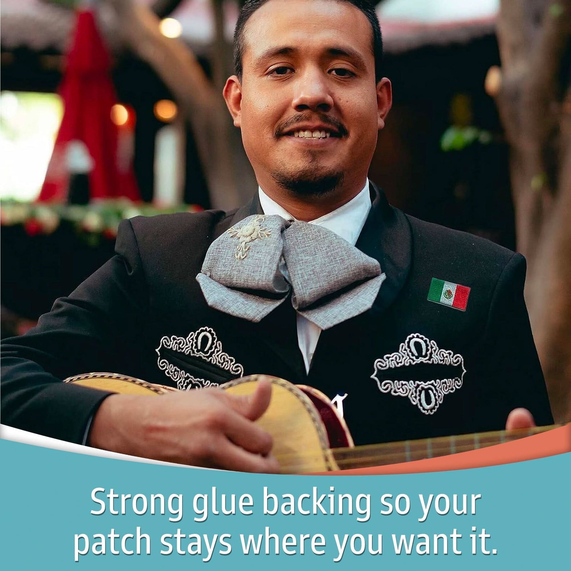 A man in a mariachi suit smiles, holding an instrument with a Laughing Lizards Small Mexican Flag Patch (5-Pack) embroidered on his jacket. Text below reads: “Strong glue backing keeps your patch in place.”.