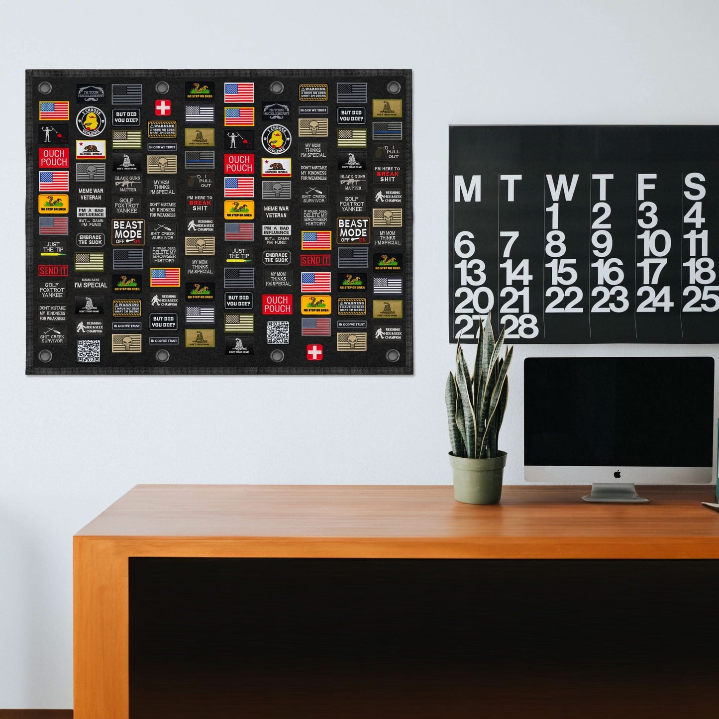 A minimalist home office with a desk, an iMac, a calendar, and a Tactical Patch Display Board Holder featuring various patches.